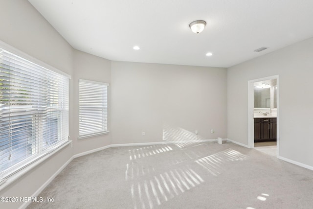 spare room with light carpet, visible vents, baseboards, and a sink