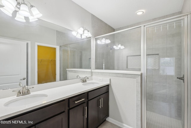 bathroom featuring double vanity, a stall shower, a spacious closet, and a sink