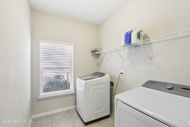 laundry area featuring light tile patterned floors, laundry area, washing machine and dryer, and baseboards