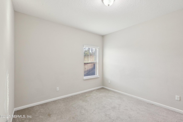 empty room featuring carpet, a textured ceiling, and baseboards