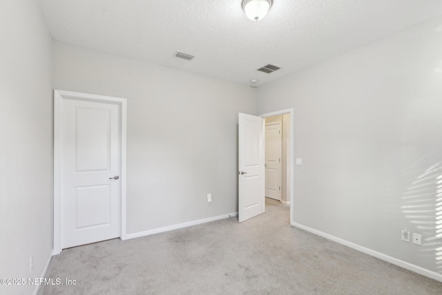 unfurnished bedroom with a textured ceiling, carpet floors, and visible vents