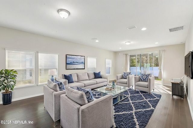 living room with dark wood-style floors, visible vents, and baseboards