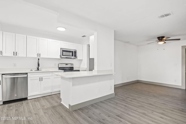 kitchen with visible vents, appliances with stainless steel finishes, light countertops, light wood-type flooring, and white cabinetry