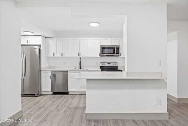 kitchen featuring a sink, appliances with stainless steel finishes, white cabinets, and light countertops