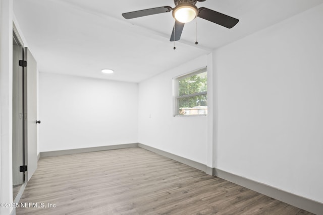 spare room with baseboards and wood finished floors