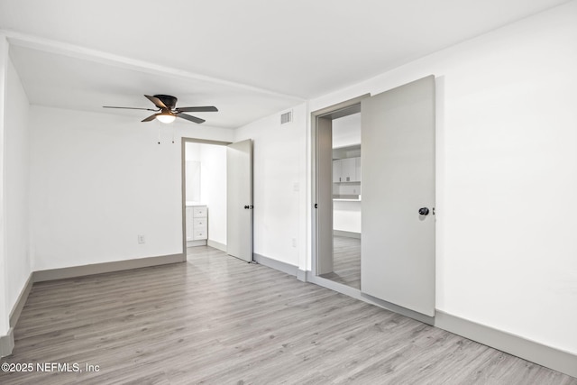 unfurnished bedroom featuring baseboards, visible vents, wood finished floors, and ensuite bathroom