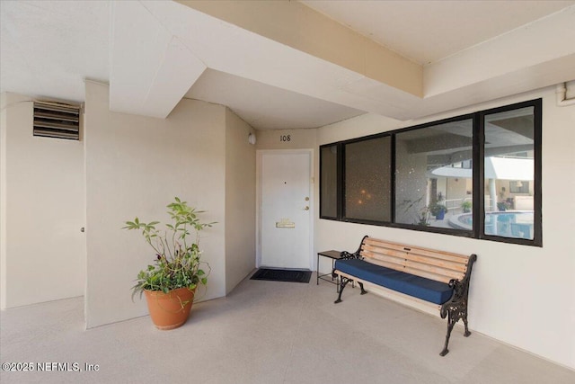 view of exterior entry with visible vents and stucco siding