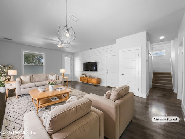 living room with dark wood-style flooring, visible vents, baseboards, and stairs