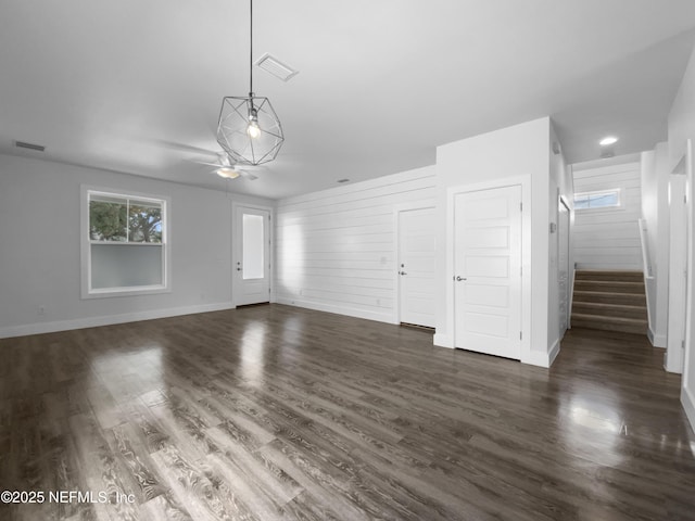 unfurnished living room with stairs, dark wood-type flooring, and visible vents