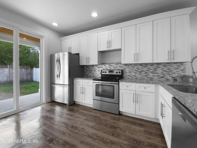 kitchen featuring decorative backsplash, appliances with stainless steel finishes, white cabinets, a sink, and light stone countertops