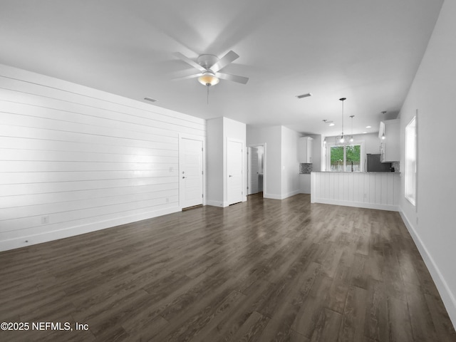 unfurnished living room with baseboards, dark wood-type flooring, visible vents, and a ceiling fan