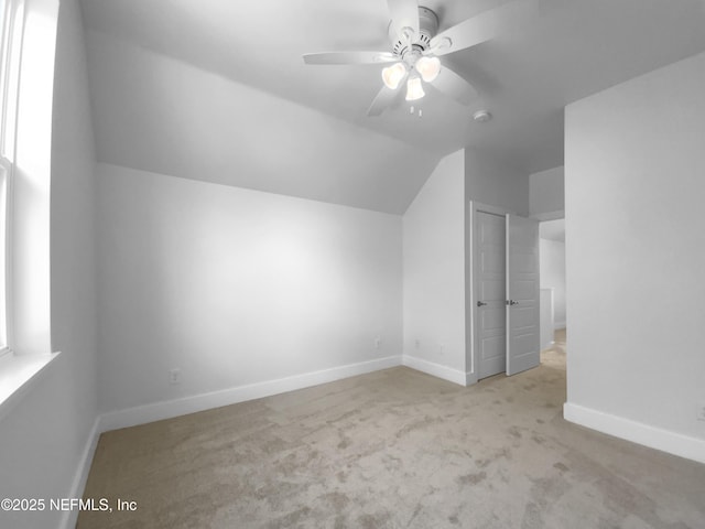 additional living space with lofted ceiling, carpet, a ceiling fan, and baseboards