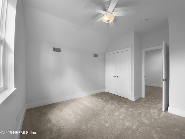 unfurnished bedroom featuring visible vents, vaulted ceiling, a closet, and carpet flooring