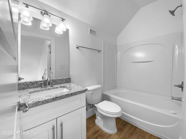 bathroom with lofted ceiling, toilet, wood finished floors, vanity, and visible vents