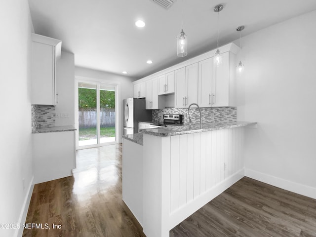 kitchen featuring a peninsula, white cabinetry, appliances with stainless steel finishes, and dark wood-style flooring