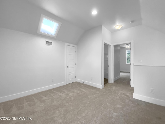 bonus room featuring carpet, vaulted ceiling with skylight, visible vents, and baseboards