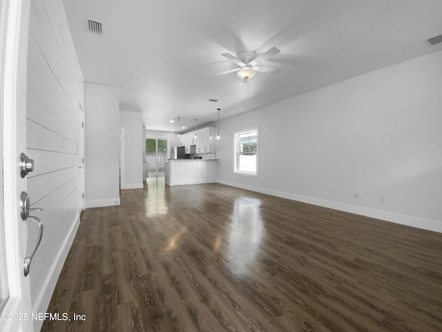 unfurnished living room with baseboards, visible vents, a ceiling fan, and dark wood-type flooring