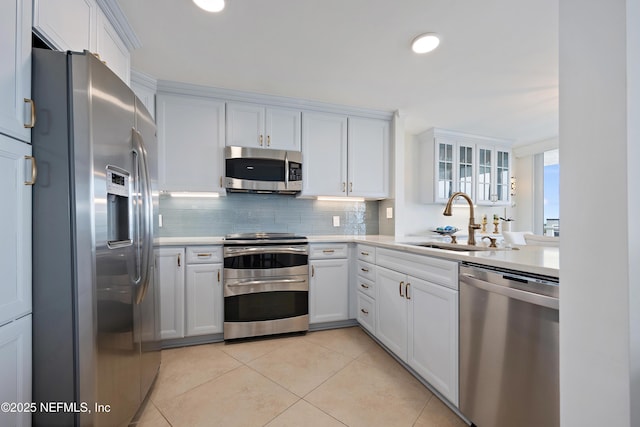 kitchen with a sink, white cabinets, light countertops, appliances with stainless steel finishes, and backsplash