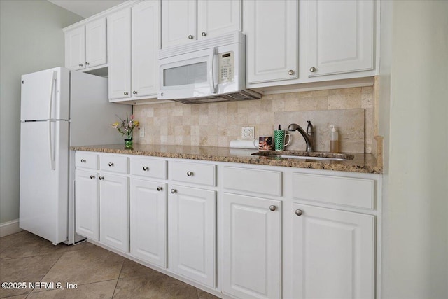 kitchen with decorative backsplash, white cabinetry, a sink, light tile patterned flooring, and white appliances