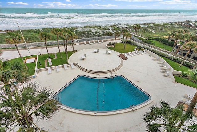 view of swimming pool with a water view and fence