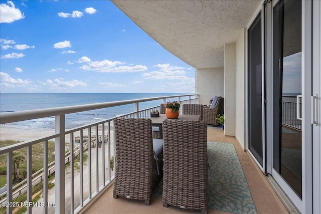 balcony with a water view and a view of the beach