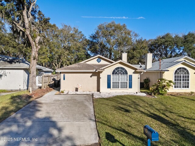 ranch-style home featuring fence, a chimney, and a front lawn