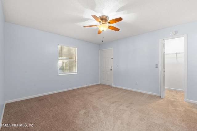 unfurnished room featuring ceiling fan, baseboards, a textured ceiling, and light colored carpet