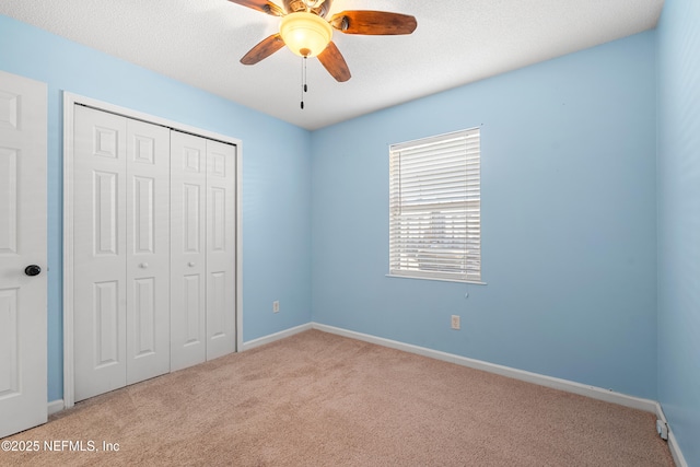 unfurnished bedroom featuring carpet, baseboards, ceiling fan, and a closet