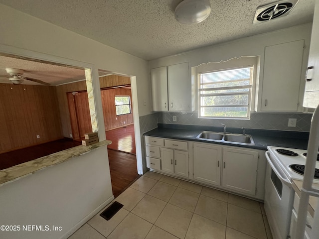 kitchen with light tile patterned floors, a sink, visible vents, white cabinets, and white range with electric stovetop