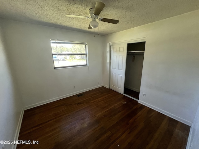 unfurnished bedroom with a textured ceiling, visible vents, baseboards, a closet, and dark wood finished floors