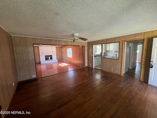 unfurnished living room featuring a brick fireplace, a textured ceiling, a ceiling fan, and dark wood-type flooring