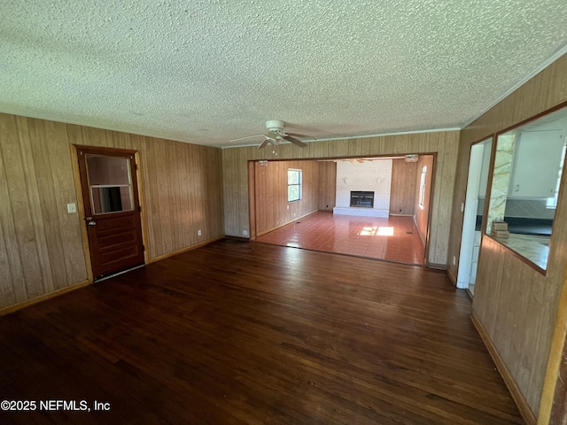 unfurnished living room with a fireplace, ceiling fan, a textured ceiling, wood finished floors, and baseboards