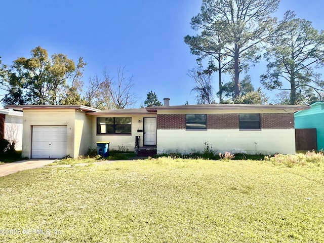 single story home featuring a garage, driveway, a front lawn, and concrete block siding