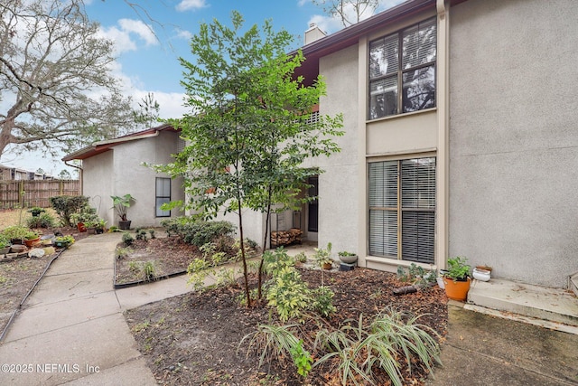 exterior space with fence, a chimney, and stucco siding