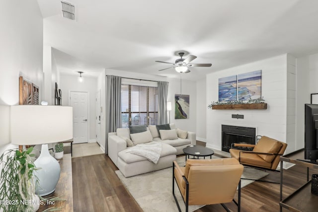 living room featuring baseboards, visible vents, ceiling fan, wood finished floors, and a fireplace