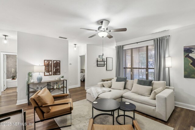 living area featuring visible vents, ceiling fan, baseboards, and wood finished floors