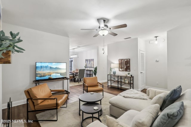 living area with ceiling fan, wood finished floors, visible vents, and baseboards