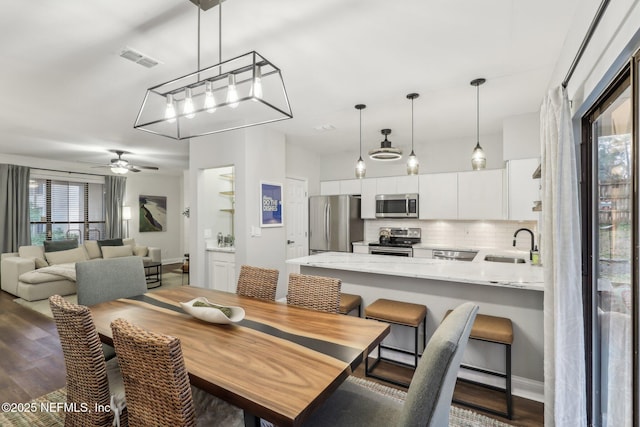 dining space with dark wood-style floors, visible vents, and a ceiling fan