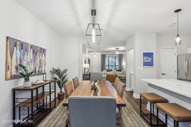 dining space featuring dark wood-style floors, ceiling fan, and baseboards