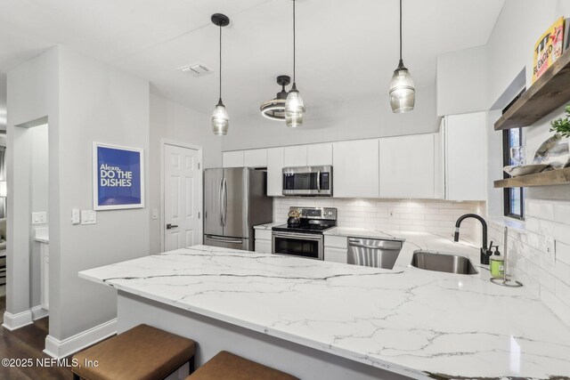 kitchen featuring stainless steel appliances, backsplash, a sink, and a peninsula