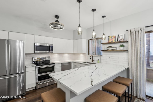 kitchen with a breakfast bar area, tasteful backsplash, appliances with stainless steel finishes, a sink, and a peninsula