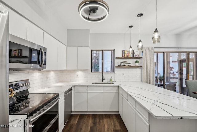 kitchen with light stone counters, appliances with stainless steel finishes, decorative backsplash, and a sink