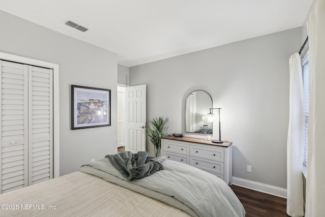 bedroom featuring dark wood-style flooring, a closet, visible vents, and baseboards