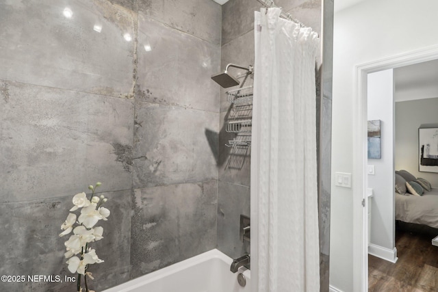 ensuite bathroom featuring baseboards, ensuite bath, wood finished floors, and shower / tub combo with curtain