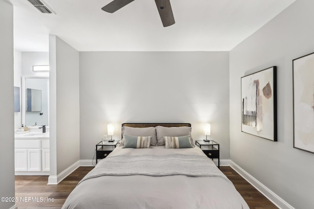 bedroom featuring ensuite bathroom, dark wood-type flooring, visible vents, and baseboards