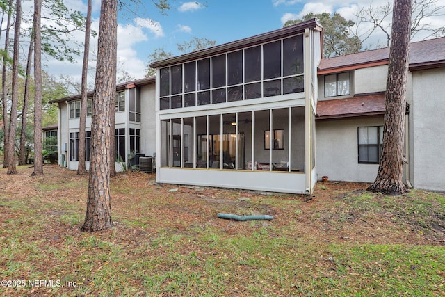 rear view of house featuring cooling unit, a sunroom, and stucco siding