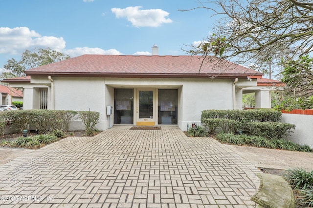 rear view of property with roof with shingles and stucco siding