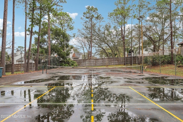 exterior space with a tennis court and fence