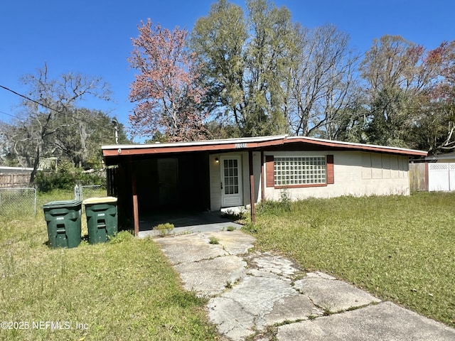 view of front of house featuring concrete driveway, concrete block siding, an attached carport, fence, and a front yard