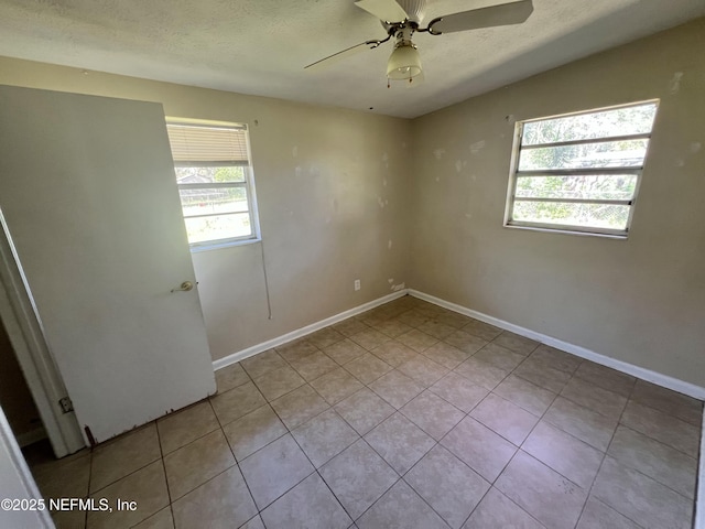 empty room with tile patterned flooring, ceiling fan, baseboards, and a textured ceiling